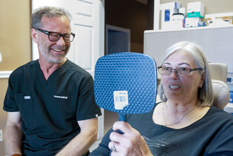 woman with new teeth and looking in mirror